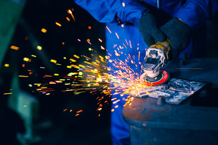 Closeup heavy steel worker using electric wheel grinding disc cuting metal plate in workplace danger...