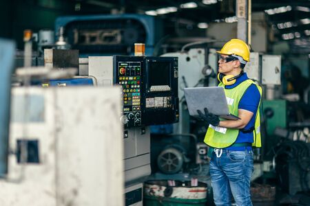 Asian engineer programming the machine in factory with laptop computer to setup program process.の写真素材