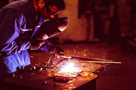 Steel industry worker welding metal piece reinforcement with welding rod fire sparking, Danger at work concept.の写真素材