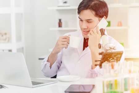 scientist relax working in the morning check the e-mail drink hot coffee and calling with friendの写真素材