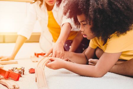 Single mom living with two daughter learning and playing puzzle toy in home apartment. Nanny looking or childcare at living room black people.の写真素材