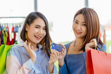 Asian girls enjoy shopping with cashless credit card payment with friend happy moment fun in sale shop together.の写真素材