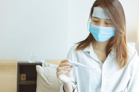 Asian teen Coronavirus flu infected looking at digital thermometer anxiously that would be infected...