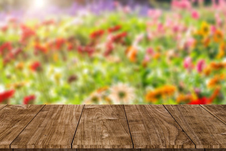 blur colorful flower field with wooden table top blank space for natural aroma or perfume products...