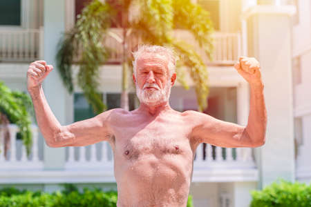 Strong healthy elder man show muscle and fit expression outdoorの写真素材