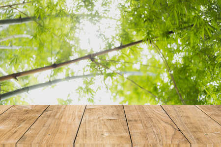 blur bamboo forest green tree with wooden table top for products montage advertising backgroundの写真素材