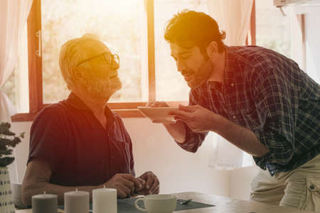 Happy senior elderly man enjoy cooking with family at the kitchen stay home leisure activity and people lifestyleの写真素材