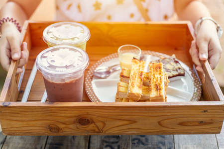 Hand serving set of bread butter toast and ice chocolate sweet food at Thailand cafe.の写真素材
