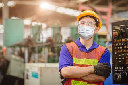 Asian worker wearing disposable face mask or HEPA face shield for protection from Coronavirus(Covid-19) spreading and toxic smoke dust air pollution in factory for labor health care.の写真素材