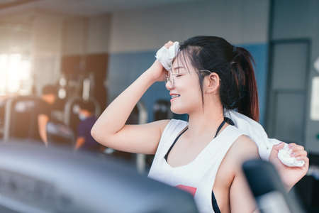 Asian braces girl using towel wiped her sweat after exercise in sport club every morning, she feel happy and smile after workout.の写真素材