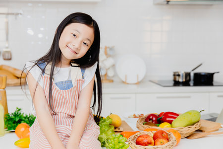 Portrait little cute girl child sitting on the table kitchen room backgroundの写真素材