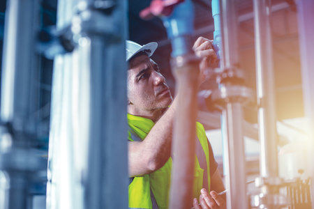 factory engineer worker repair and checking high pressure water pipe in factory boiler roomの写真素材