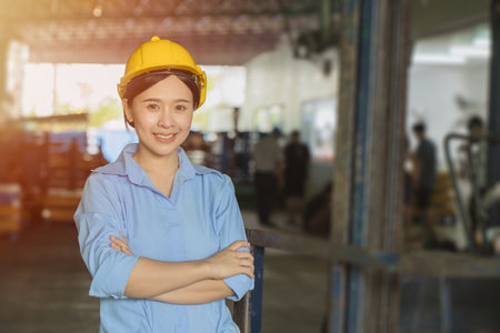 Young Asian smart woman working as foreman head engineer manager at logistic warehouse portrait smiling arms crossed.の写真素材