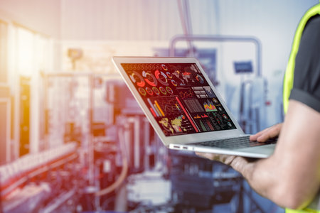 closeup engineer using laptop computer to monitor and checking business data with blur factory backgroundの写真素材