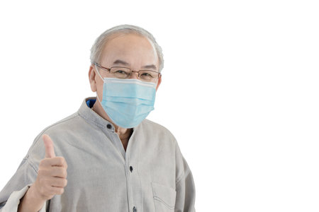 Asian senior elder man with face mask hand showing thumbs up isolated on white background with...