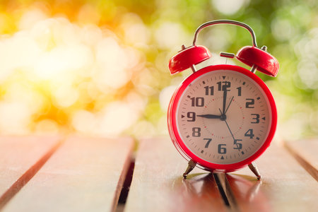 9 o'clock Classic Alarm Clock  on Wood Table with Sun Light green background.