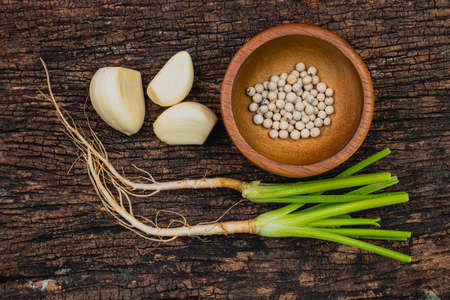 Coriander root Garlic and Pepper seeds or Three kings of Thai food ingredient shot on wooden old rustic background.の写真素材