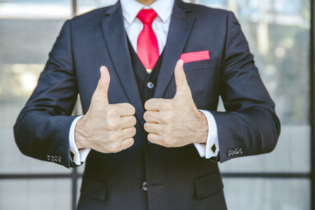Two thumbs up business man close up at hand. male in suit show good best successful gesture.の写真素材