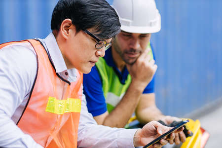 Workers closely monitor Covid breaking news on the phone. People reading and update new information from social media in real time on smartphone seriously.の写真素材