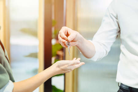 Male hand giving return apartment or home room key to women.の写真素材