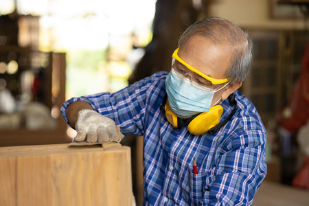 Elder worker wood woodcraft retire hobby for good retirement, Asian male mature professional master of making wooden furniture with face mask protective.の写真素材