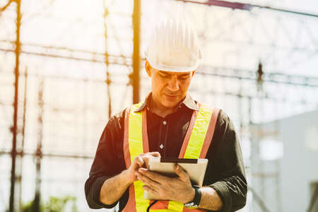Foreman builder engineer worker using tablet computer to check building floor plan at construction site.の写真素材