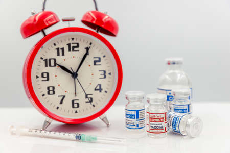Covid Vaccine dose bottle with Time clock for Coronavirus Vaccination timing concept.の写真素材
