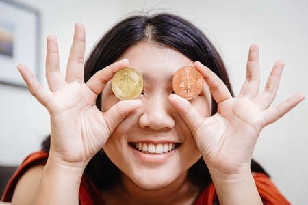 teen girl holding bitcoin at eyes for happy looking market vision to trading cryptocurrency conceptの写真素材