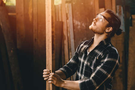 Young carpenters man new generation business wood worker making furniture choosing the right woodの写真素材