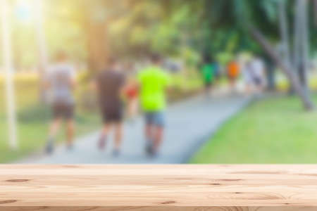 Blur people running in the park with wooden table top foreground for sport products montage backgroundの写真素材