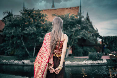 Women wear traditional Thai dress cloth back view standing by river and vintage Thai style home.の写真素材