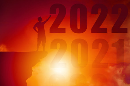 Silhouette male hand rise at cliff with year 2022 Sun rising - New hope next challenge and better...
