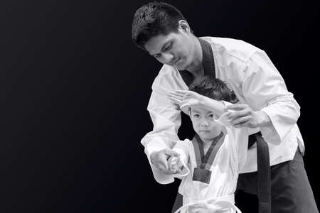 Taekwondo master black belt teaching kid to fight guard on black backgroundの写真素材