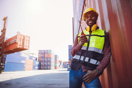 Portrait staff worker happy smile working in cargo shipping logistic port hand holding radio control.の写真素材