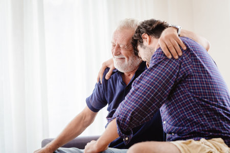 old father elder grateful happy smile and embrace his son at homeの写真素材