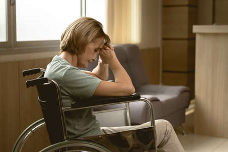 adult women patient feel sad lonely sitting on wheelchair at hospital homecare dim lightの写真素材