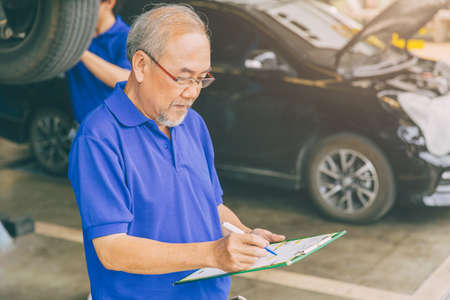 Asian professional adult garage owner working checking customer carの写真素材