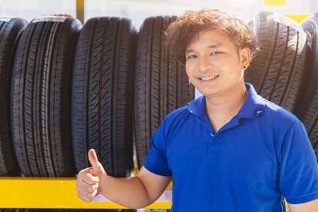 Car tire on shelf with salesman sale agent happy to service in tyre shop. Good quality vehicle tire, people recommended and promotion.の写真素材