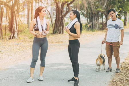 Lady wife girl gossip with friend while morning jogging. Husband man look suspiciously and puzzled.の写真素材