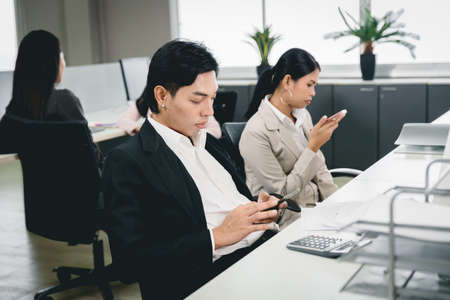 Office employee playing smartphone at work and social media addicted bad habit for business company problem.の写真素材