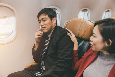 Asian businessman male motion sick health problem during fly on board in flight cabin.の写真素材