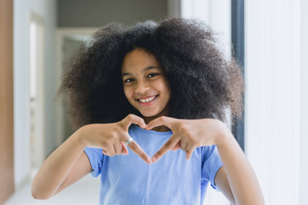 black teen girl afro hair happy smile with hand love heart sign.の写真素材