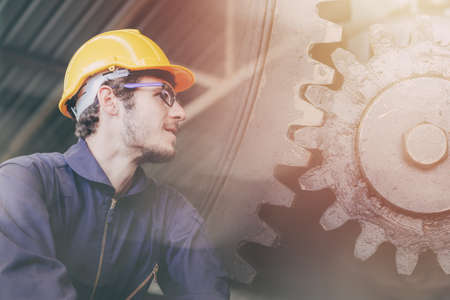 Caucasian Engineer staff worker working overlay with metal gear cogwheel for people run industry banner background.の写真素材