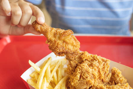 closeup people eating fried chicken with potato stick french fries American style fatty food.の写真素材