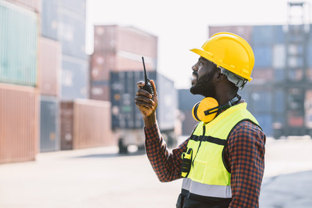 black worker African working engineer foreman radio control in port cargo shipping customs container...