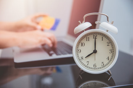 hand typing credit card number with time clock for online shopping times conceptの写真素材