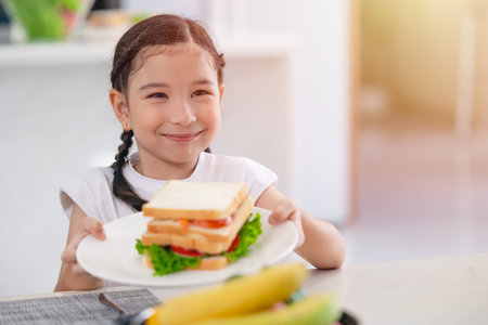 Asian cute daughter happy enjoy eating healthy food morning meal vegetable salad sandwichの写真素材