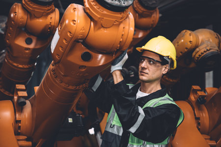 Engineer team service fix robot welding arm working in automation factory. People worker work in robotic arm assembly plant heavy metal industry.の写真素材