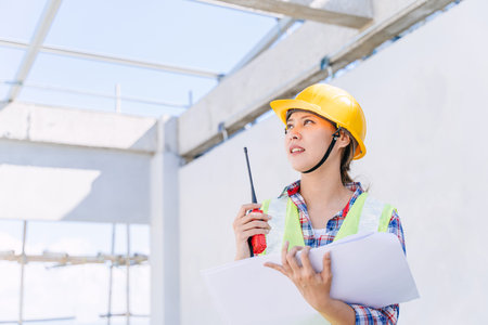 Asian woman engineer worker work in construction site. Smart builder architect female in safety...