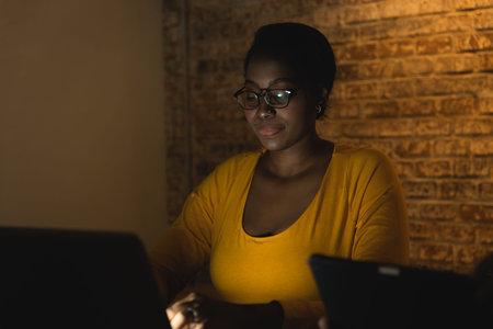african black business woman night working on laptop computer hard work overnight